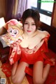 A woman in a red dress sitting on a bed holding a monkey.