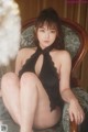 A woman in a black lingerie sitting on a chair.