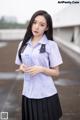 A woman in a school uniform holding a water bottle.