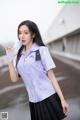 A woman in a purple shirt and black skirt holding a water bottle.