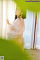 A woman in a white dress standing by a window.