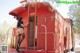 A woman in stockings and high heels standing on a red caboose.