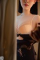 A woman in a black and white lingerie looking at herself in the mirror.