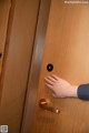 A person is opening a wooden door with their hand.