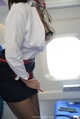 A woman in a white shirt and black skirt on an airplane.