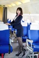 A woman in a business suit standing in an airplane.