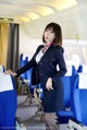 A woman in a business suit standing in an airplane.