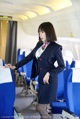 A woman in a business suit standing in an airplane.