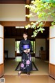 A woman in a black and purple kimono standing in a room.