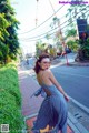 A woman in a blue and white dress is walking down the street.