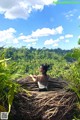 A woman sitting on top of a nest in the middle of a forest.