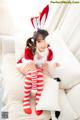 A woman in a red and white striped outfit sitting on a white couch.