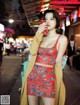 A woman in a red dress drinking from a red cup.