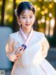 A young girl in a white and pink hanbok poses for a picture.