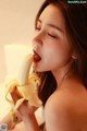 A woman is eating a banana with her mouth open.