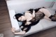 A woman laying on a white couch wearing a black lingerie.