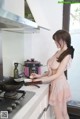 A woman in a pink lingerie preparing food in a kitchen.