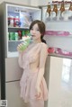 A woman in a pink dress holding a bottle of soda.