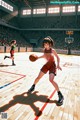 A woman in a red uniform dribbling a basketball on a court.