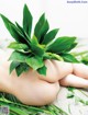 A woman's hand holding a green plant on the ground.