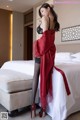 A woman in a red robe standing on a bed.