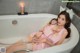 A woman sitting in a bathtub with a candle in her hand.