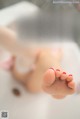 A woman laying in a bathtub with her feet up.