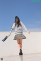 A woman in a school uniform is walking on a concrete surface.