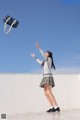 A woman in a school uniform throwing a bag in the air.