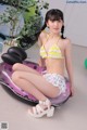 A woman in a bikini sitting on an inflatable pool float.